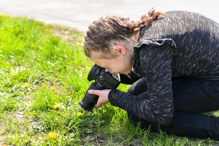 The girl takes a macro photo on a SLR camera in the park.の写真素材