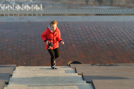 A young girl photographs nature in the park with a SLR camera.