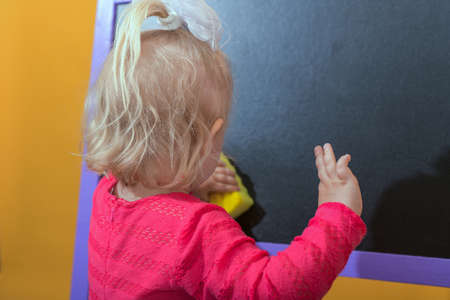 A wet sponge in the hand of a child wiping a blackboard.の写真素材