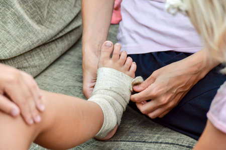 Mom will bandage the wound on her little child's leg.の写真素材