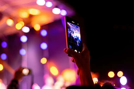 People at the holiday are filming a concert on a smartphone.の写真素材