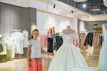 A girl near a white dress in a wedding salon.の写真素材