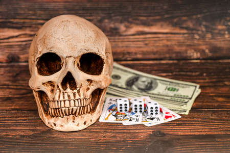Skull, dollars and playing cards on a dark wooden background, money gambling.の写真素材
