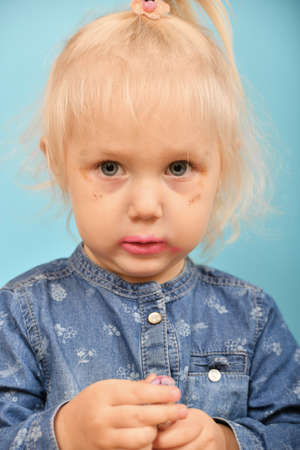 Portrait of a glamorous, self-made-up child on a blue background.の写真素材