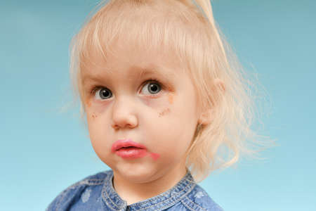 Portrait of a glamorous, self-made-up child on a blue background.の写真素材