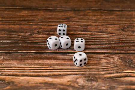 White dice are scattered on a wooden texture. Casino and gambling concept.