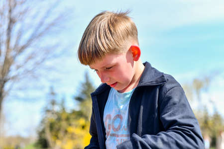 The boy fell while walking in the park and cries with tears.