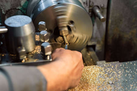 The turner cuts the bronze hexagon blanks on the lathe.の写真素材