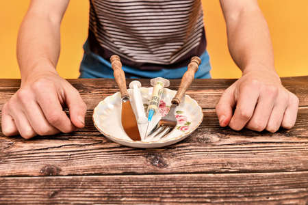 A syringe with a dollar is on a plate, a fork and a knife are nearby.の写真素材