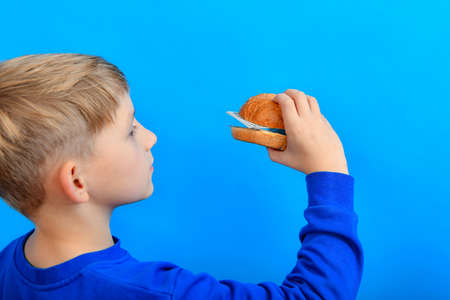 The boy eats a burger made of bread and dollars.の写真素材