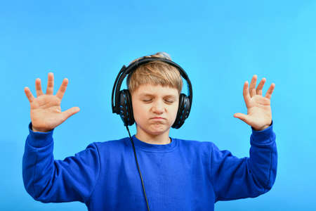 A boy in big headphones with closed eyes enjoys listening to music.の写真素材