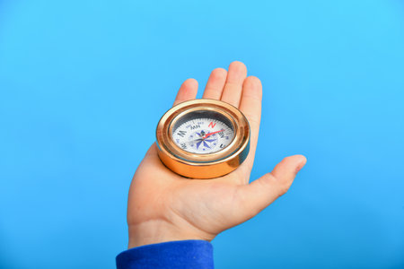 The child holds a compass in his hand on a blue background.の写真素材