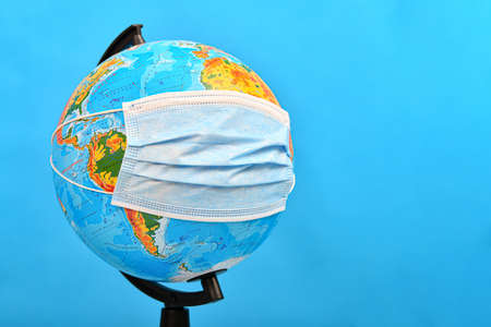 A medical mask is worn on the globe. Concept of viral infection and disease around the world.の写真素材