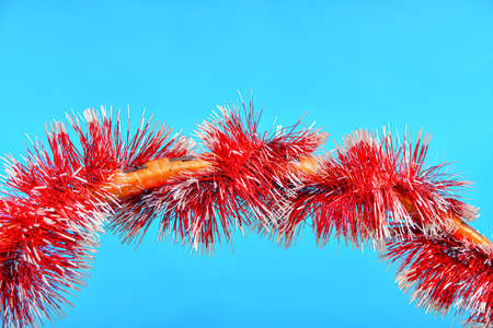Christmas tinsel is wrapped around the wooden handle of a gift basket.