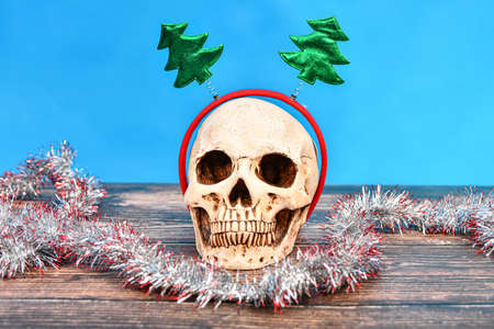 Festive New Year's skull and tinsel lie on a wooden texture.の写真素材