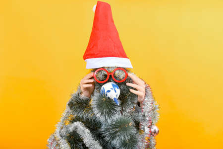 Funny Christmas tree with human hands straightens red glasses.