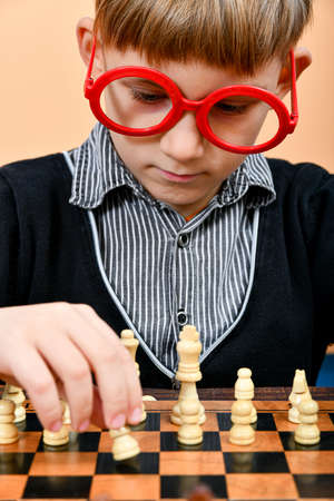 The beginning of a new game of chess with a young smart chess player in red glasses.の写真素材