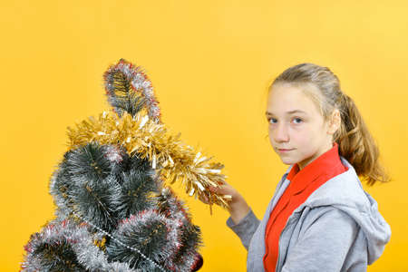 Teen girl decorates the Christmas tree with various festive toys.の写真素材