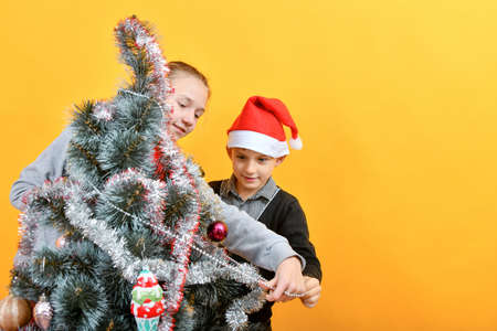 Children decorate the Christmas tree with various toys for the holiday.