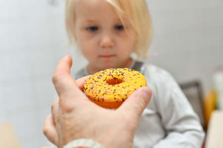Dad gives his little daughter a sweet iced donut.の写真素材