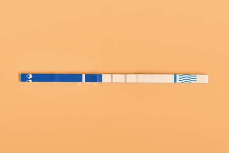 Stick with a positive pregnancy test on a beige background.