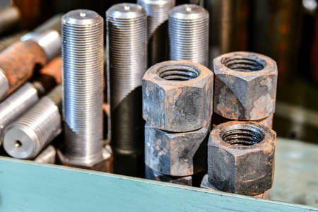 Hardened nuts on a rack before tapping on a lathe.