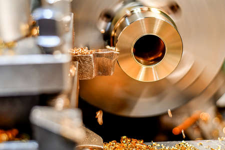A turner makes a bronze bushing on a lathe by removing chips with a mechanical cutter.の写真素材