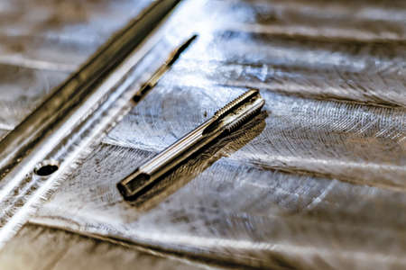 Tapping a hole with an oil-lubricated hand tap in a locksmith's shopの写真素材