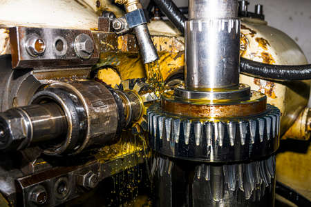 Making gears on a gear cutting machine. Machine oil cools the cutting process of the gear wheel with...