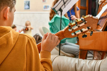 A child plays a six-string guitar at home.の写真素材
