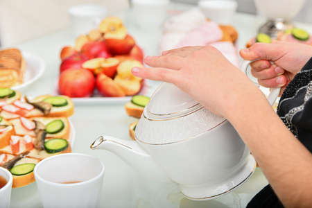 Cooking and drinking tea with sandwiches in the kitchen at the table.の写真素材