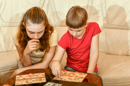 Little friends play loto game. Calm and friendly children play board games.