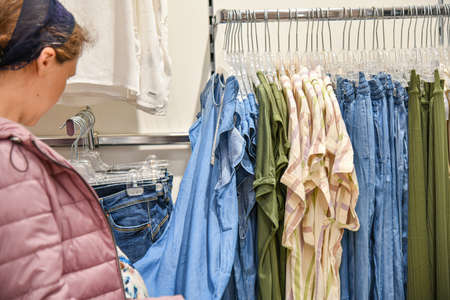 A woman chooses new things for clothes in a shopping mall.の写真素材