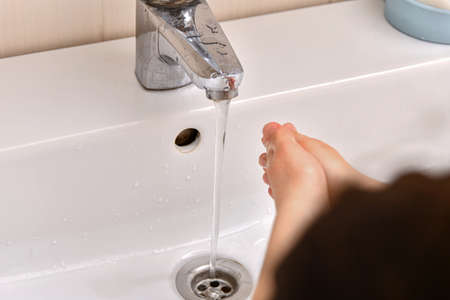 The child washes his hands with tap water.