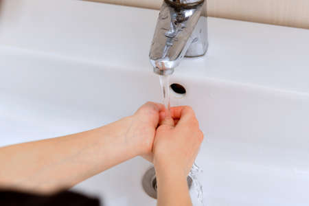 The child washes his hands with tap water.