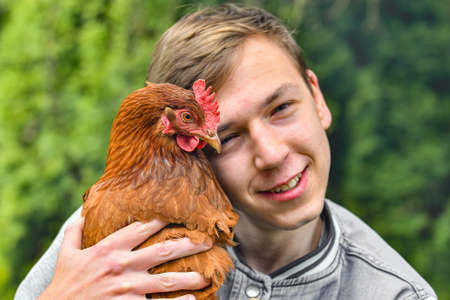 Portrait of a guy with a chicken in his hands.の写真素材