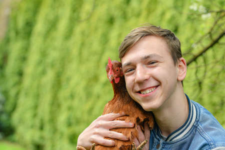Portrait of a guy with a chicken in his hands.の写真素材