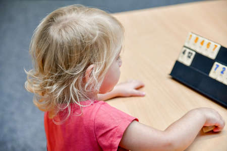 A little girl in elementary school learns numbers and puts chips in order.の写真素材