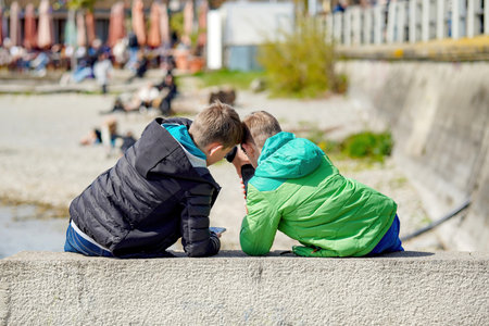 Two teenage boys are playing with phones in the park.の写真素材