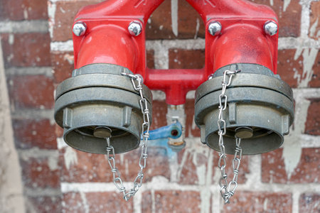 Hydrant with two taps for quick collection of water on a brick wall.