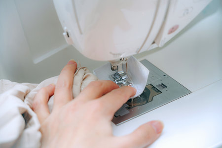 A woman seamstress sews things from fabric on a CNC sewing machine.の写真素材