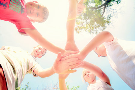 Friends hold hands together, bottom view of a group of people clasped hands.