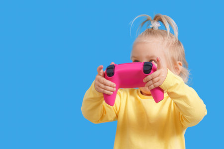 A joystick from a game console in the hands of a child, cheerful emotions in a little girl.
