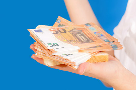 The girl is holding a piece of bread in her hands and euro banknotes on top.の写真素材