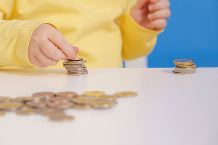A girl collects and counts coins scattered on the table.の写真素材