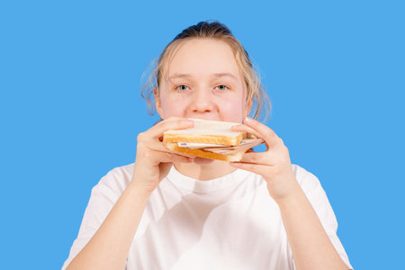 A girl eats a sandwich made from bread and banknotes.の写真素材