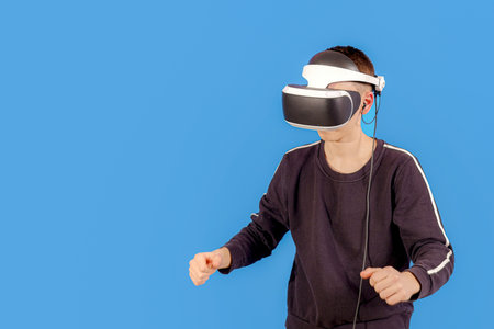 A boy in a VR helmet on a blue background is going to play computer games.の写真素材