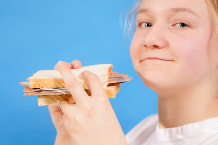 The girl made a burger from bread and is trying to eat it.の写真素材