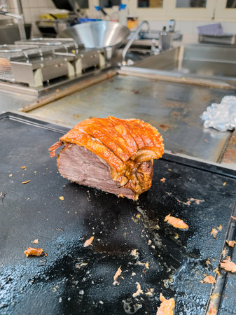 Fried piece of boiled pork meat on a cutting board in the kitchen in a restaurant.の写真素材