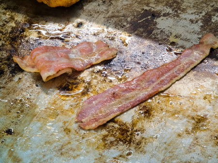 Ham and bacon are fried on the stove in a restaurant.の写真素材